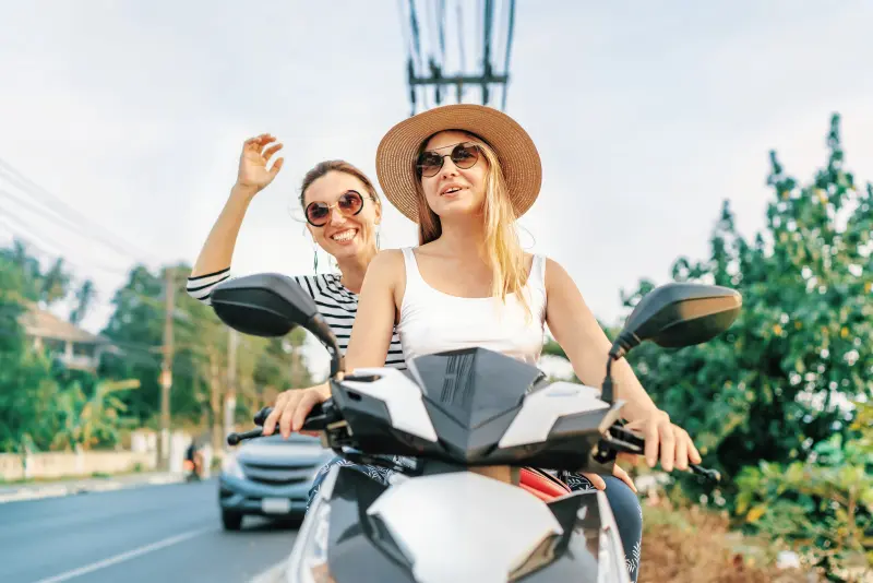 2 kaukasische Frauen auf einem Roller in Thailand - ohne Helm und Schutzausrüstung