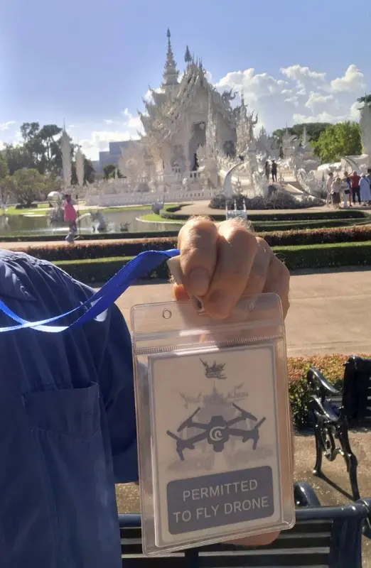 Umhänger mit dem Text "permitted to fly a drone" mit dem White Temple im Hintergrund